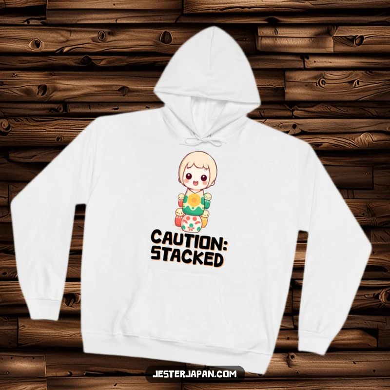 Funny kokeshi doll balancing hoodie, showing a happy character precariously stacking colorful dolls, a great funny gift idea.